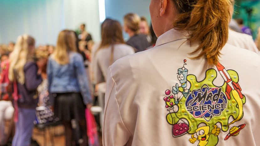 Mad scientist standing wearing a lab coat with the mad science logo on the back of the coat