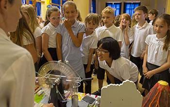 Kids gathered around a desk while the mad scientist shows them a whimehurst machine