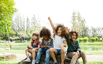 Group of children sitting on a rock in a park